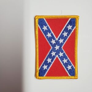 A patch of the confederate flag is hanging on a wall.