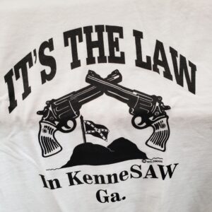 A white shirt that says it's the law in kennesaw ga.