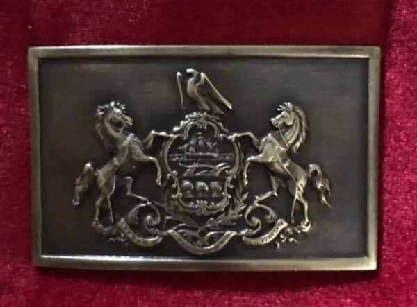 A belt buckle with a horse and rider on it.